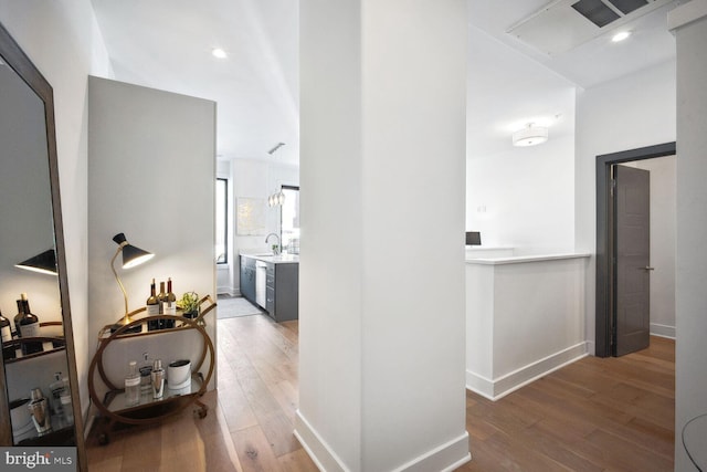 hall with a sink, wood finished floors, and baseboards