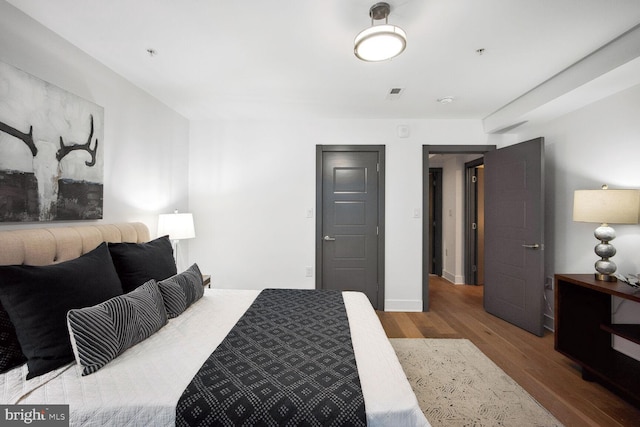 bedroom featuring baseboards, visible vents, and wood finished floors