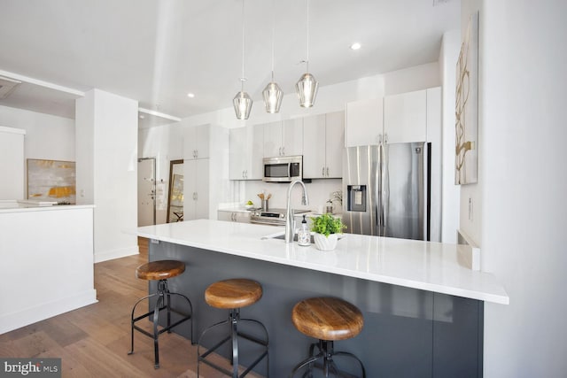 kitchen featuring appliances with stainless steel finishes, a breakfast bar, light countertops, and white cabinetry