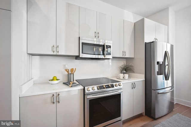 kitchen featuring dark wood-style floors, stainless steel appliances, light countertops, and white cabinetry