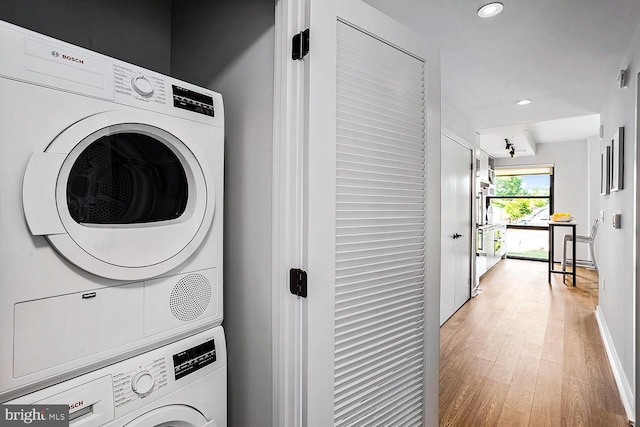 washroom with light wood finished floors, stacked washer / drying machine, recessed lighting, laundry area, and baseboards