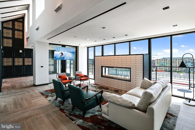 living room with expansive windows, parquet floors, a glass covered fireplace, and a city view