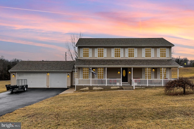 view of front of property featuring a garage, aphalt driveway, roof with shingles, covered porch, and a front yard