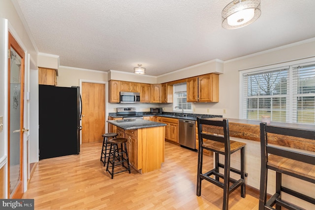 kitchen featuring stainless steel appliances, a breakfast bar, a sink, a kitchen island, and brown cabinets