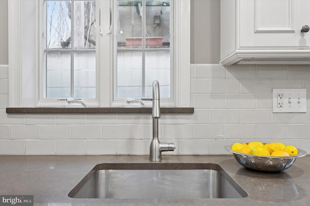 kitchen featuring tasteful backsplash, white cabinets, and a sink