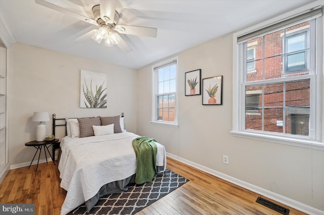 bedroom featuring visible vents, ceiling fan, baseboards, and wood finished floors