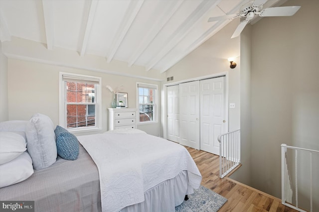 bedroom featuring lofted ceiling with beams, ceiling fan, visible vents, a closet, and light wood-type flooring