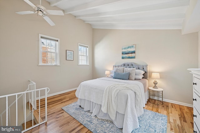 bedroom with vaulted ceiling with beams, light wood-type flooring, and baseboards