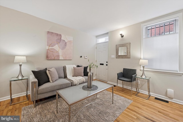 living room featuring visible vents, baseboards, and wood finished floors