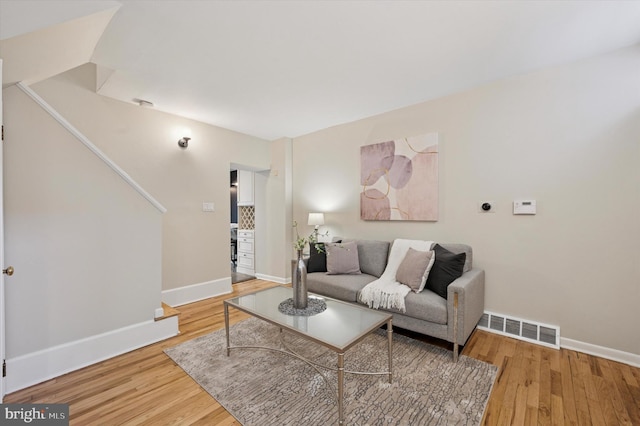 living room featuring baseboards, visible vents, and wood finished floors