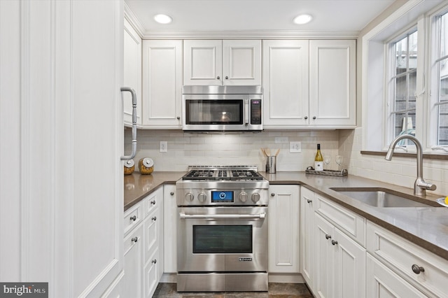 kitchen with recessed lighting, decorative backsplash, appliances with stainless steel finishes, white cabinetry, and a sink