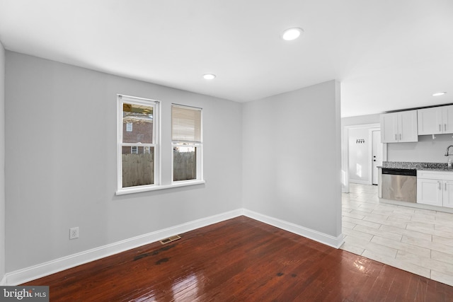 unfurnished room featuring recessed lighting, a sink, visible vents, baseboards, and light wood-type flooring