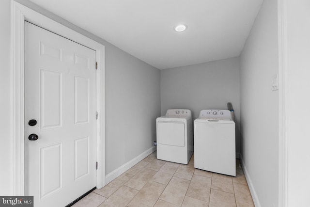 laundry room featuring laundry area, washing machine and dryer, light tile patterned floors, and baseboards