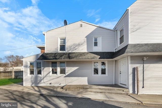 back of property featuring a shingled roof, a patio area, and fence