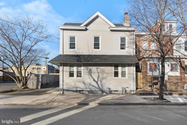 traditional home featuring roof with shingles, a chimney, and fence