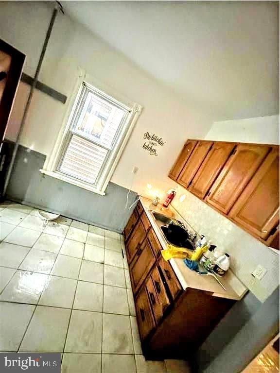 kitchen with light tile patterned floors, light countertops, and brown cabinetry