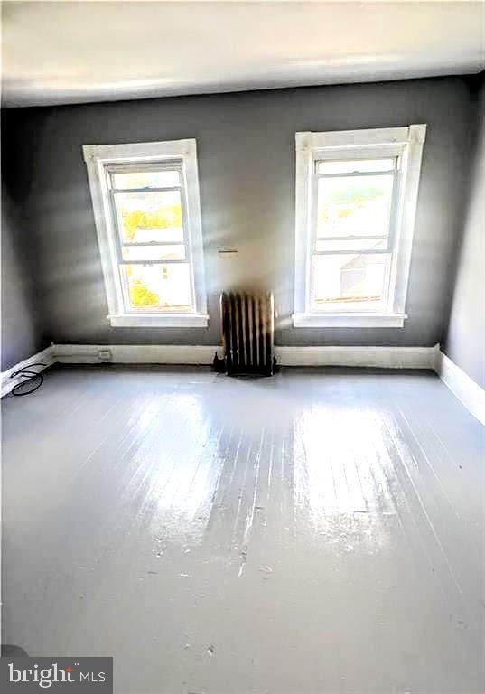 empty room featuring radiator, baseboards, and wood finished floors