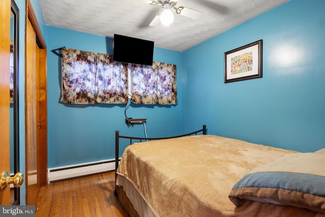 bedroom with ceiling fan, a baseboard radiator, and wood finished floors