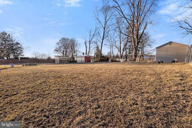 view of yard featuring a pole building, fence, and an outdoor structure