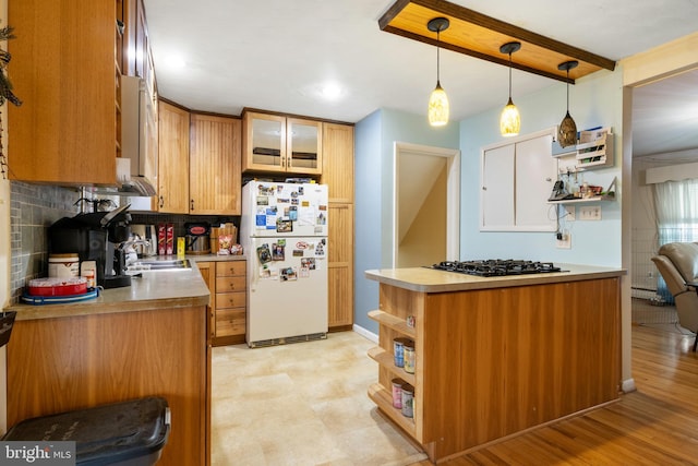 kitchen featuring black gas stovetop, a sink, hanging light fixtures, light countertops, and freestanding refrigerator