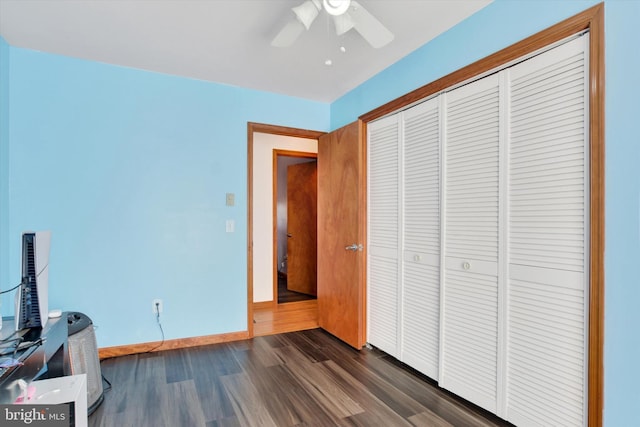 unfurnished bedroom with dark wood-style floors, a closet, baseboards, and a ceiling fan