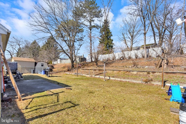 view of yard with fence, a patio, and an outbuilding