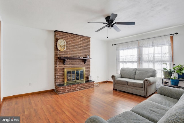 living room with ceiling fan, a fireplace, baseboards, and wood finished floors