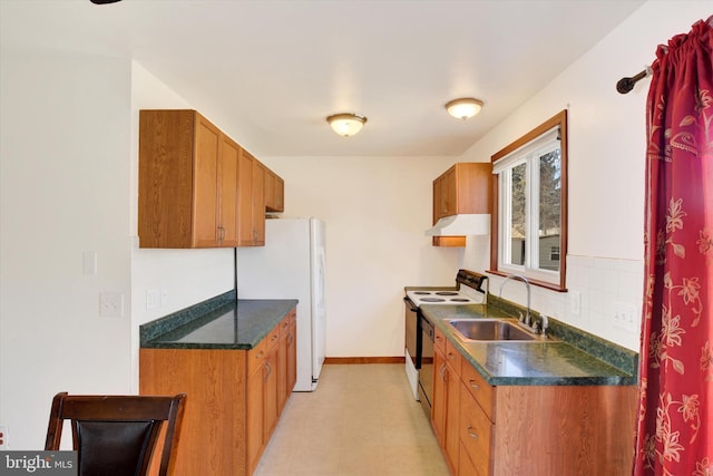 kitchen featuring electric range oven, dark countertops, freestanding refrigerator, under cabinet range hood, and a sink