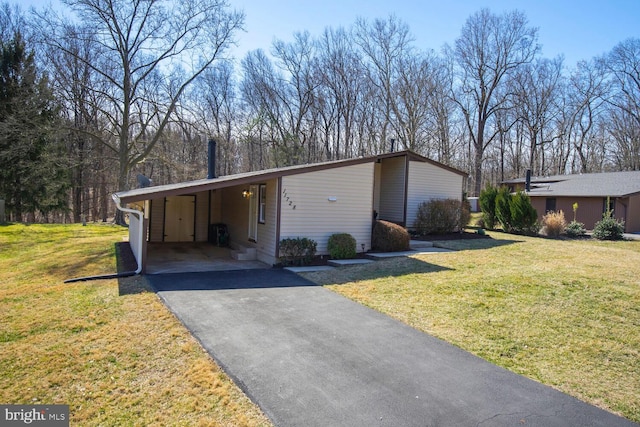 view of front facade with a front yard, an attached carport, and driveway