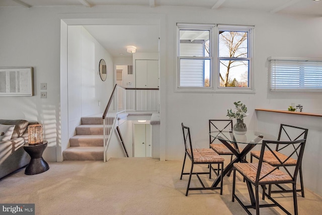 dining room with beam ceiling, stairs, and carpet floors