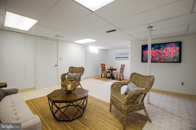 living room with a drop ceiling, baseboards, and visible vents