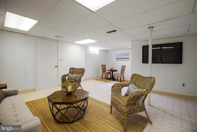 living room with light tile patterned floors, a paneled ceiling, and visible vents