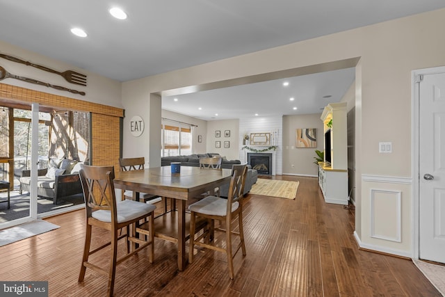 dining room with a fireplace, wood finished floors, and recessed lighting