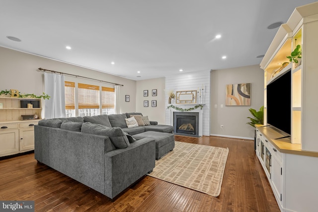 living room featuring dark wood-type flooring, a fireplace, and recessed lighting