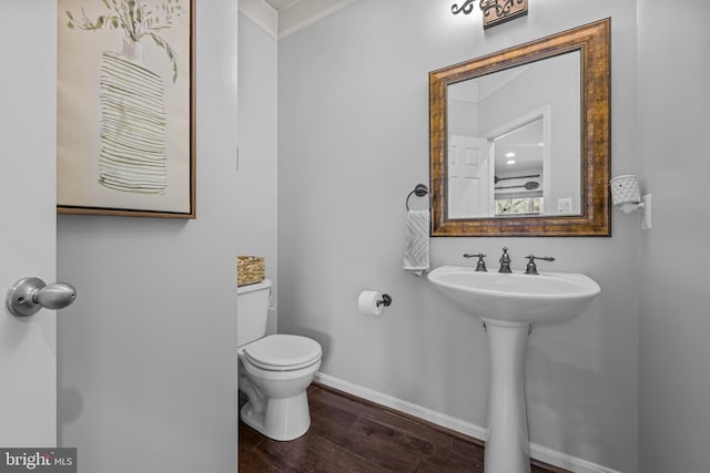 bathroom featuring toilet, a sink, baseboards, and wood finished floors