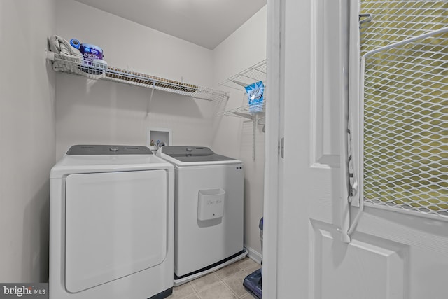 clothes washing area with laundry area, light tile patterned flooring, and washing machine and dryer