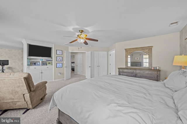 bedroom with light colored carpet, a ceiling fan, baseboards, multiple closets, and visible vents