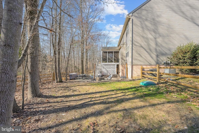 view of yard with a sunroom, fence, and stairway