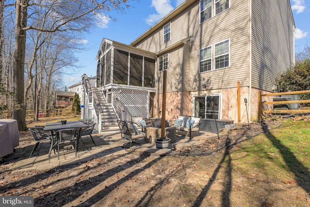 back of house with a sunroom, a patio area, stairway, and an outdoor living space