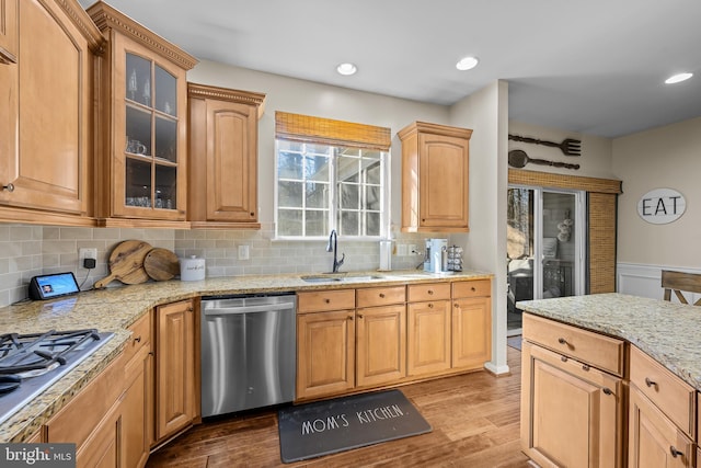 kitchen featuring stainless steel appliances, light wood-style flooring, a sink, and glass insert cabinets