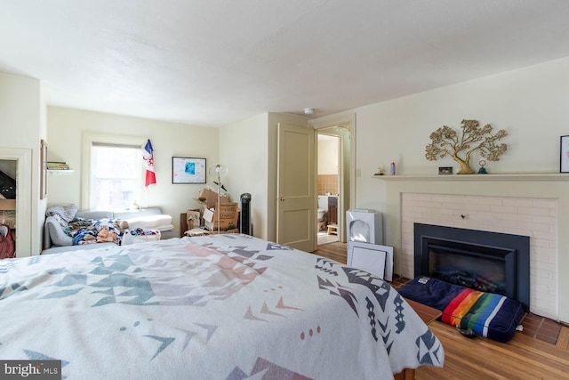 bedroom featuring a brick fireplace and wood finished floors