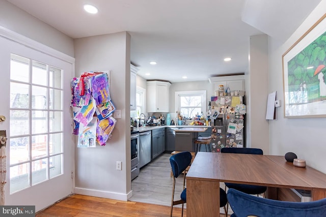 kitchen featuring gray cabinets, stainless steel appliances, light countertops, light wood-type flooring, and recessed lighting