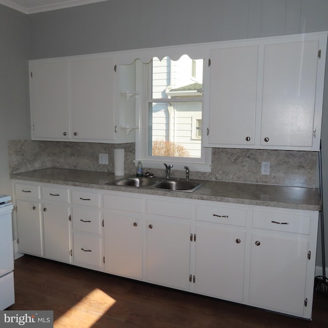 kitchen with dark wood-type flooring, decorative backsplash, a sink, and white cabinets