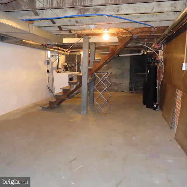 unfinished below grade area with water heater, stairway, and separate washer and dryer