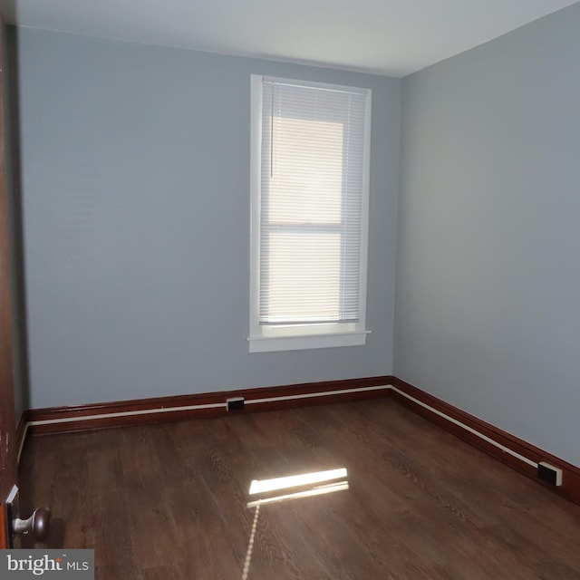 unfurnished room with dark wood-style flooring and baseboards