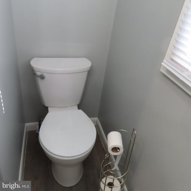 bathroom with wood finished floors, toilet, and baseboards