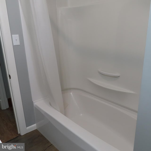 bathroom with shower / tub combo with curtain and wood finished floors