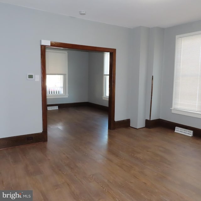 spare room with baseboards, visible vents, and wood finished floors