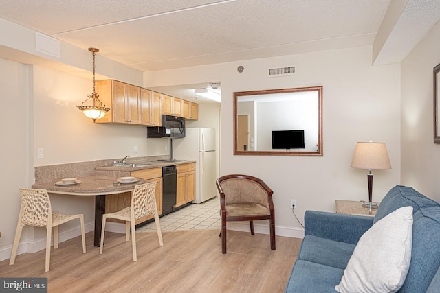 kitchen with light brown cabinets, visible vents, open floor plan, light wood-type flooring, and black appliances