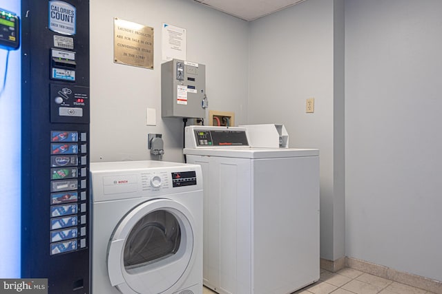 common laundry area with light tile patterned floors, washing machine and dryer, and baseboards